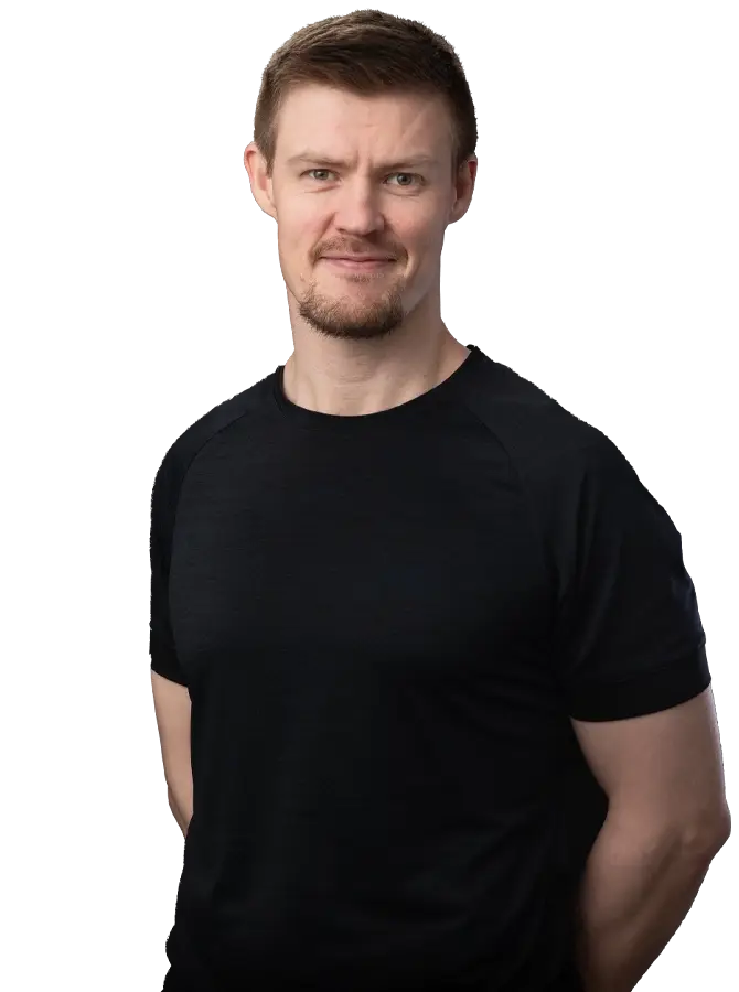 Mustapaitainen mieshenkilö katsoo kohti. Kädet selän takana.