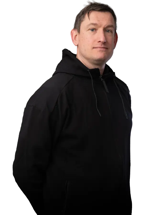 Mustapaitainen mieshenkilö katsoo kohti. Kädet selän takana.